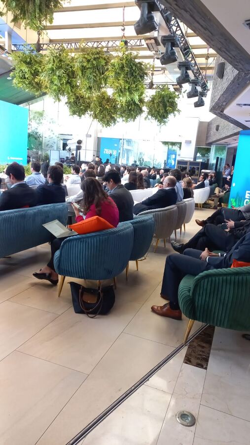 Asistentes siguiendo una presentación desde un lounge de evento corporativo