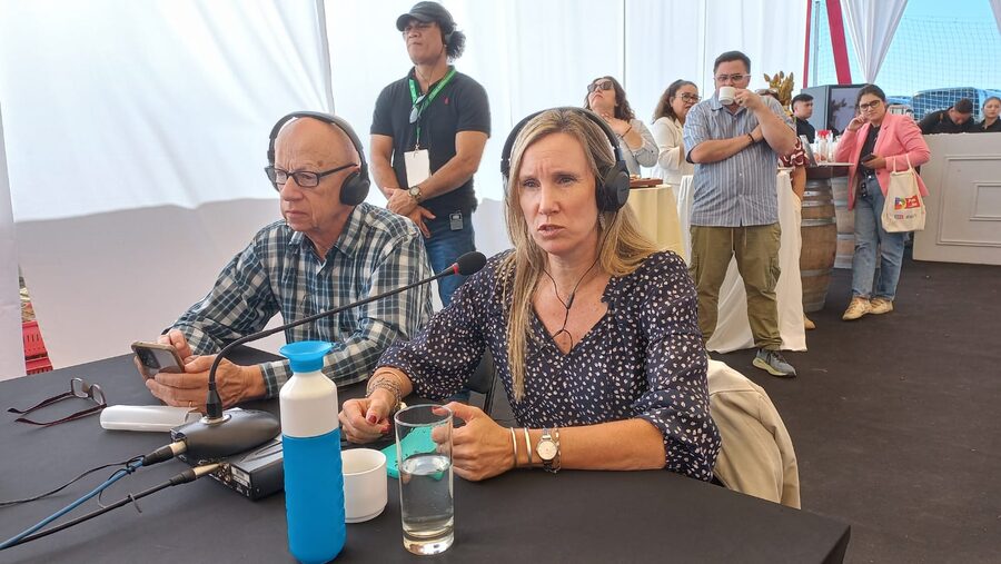 Dos intérpretes con audífonos frente a una consola de interpretación y un micrófono, trabajando durante la sesión